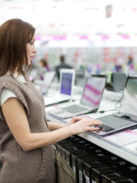 Mulher testa laptop em loja de varejo