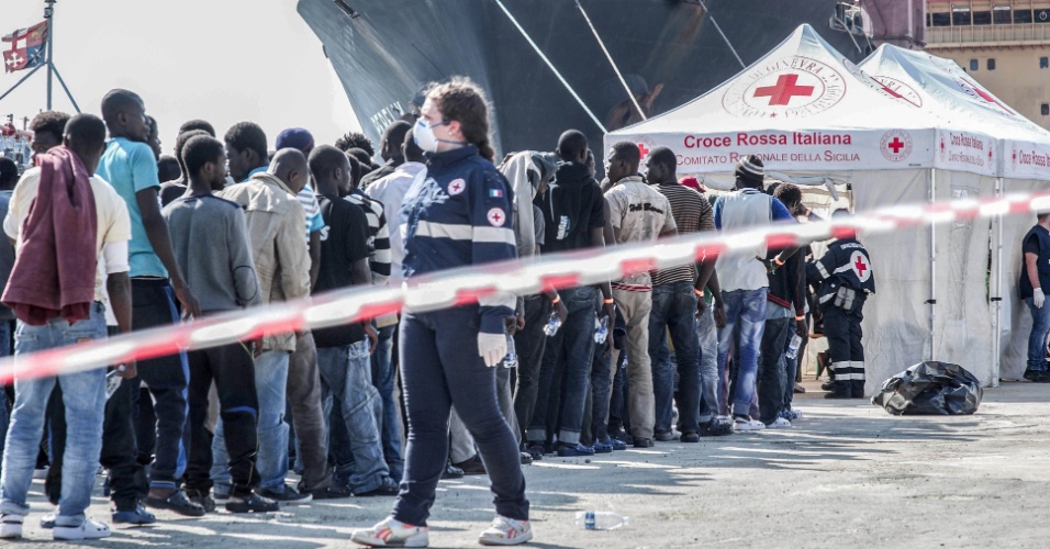 2.out.2015 - Assim que os refugiados chegam em navios no porto de Augusta, na Sicília, Itália, são organizados em filas para receber atendimento imediato da Cruz Vermelha, que pergunta sobre sintomas, dores, febre e até gravidez