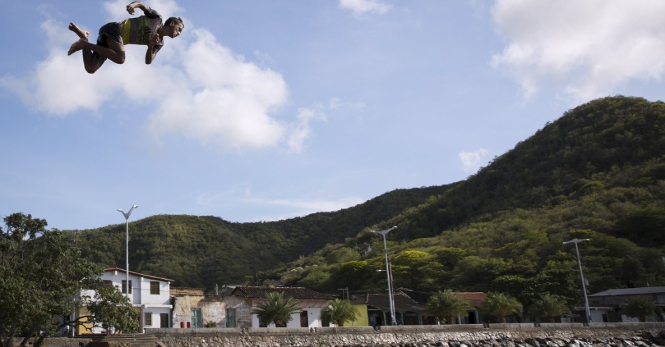 30.out.2015 - Garoto salta de telhado para cair no mar, na baía do rio Caribe, em Sucre, na Venezuela