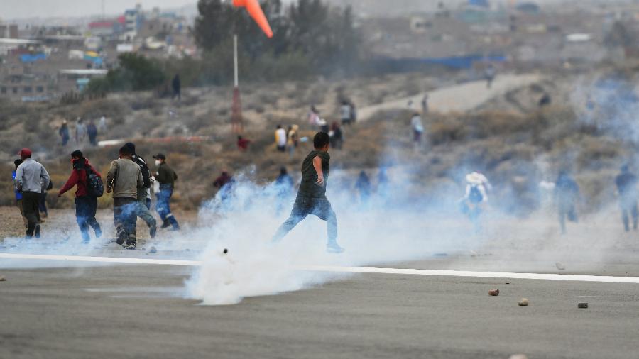 Manifestantes fogem do gás lacrimogêneo lançado pela polícia enquanto ocupam o aeroporto internacional Alfredo Rodriguez Ballon, da cidade de Arequipa - DIEGO RAMOS/AFP