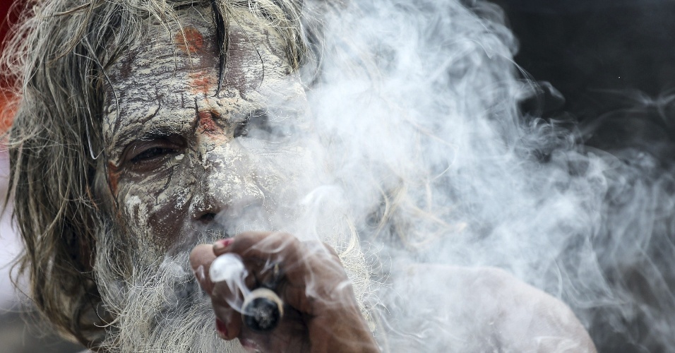 24.set.2015 - Sacerdote fuma durante um banho de purificação no rio Godavari em Nasik, na Índia