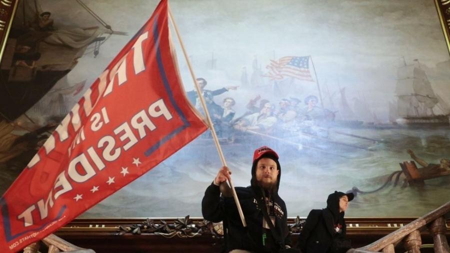 Invasor do Capitólio agita uma bandeira com os dizeres "Trump é meu presidente" em 6 de janeiro - Getty Images
