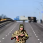 Soldado ucraniano faz patrulha em rodovia vazia no oeste da capital Kiev na manhã de sábado (26) - Daniel Leal/AFP