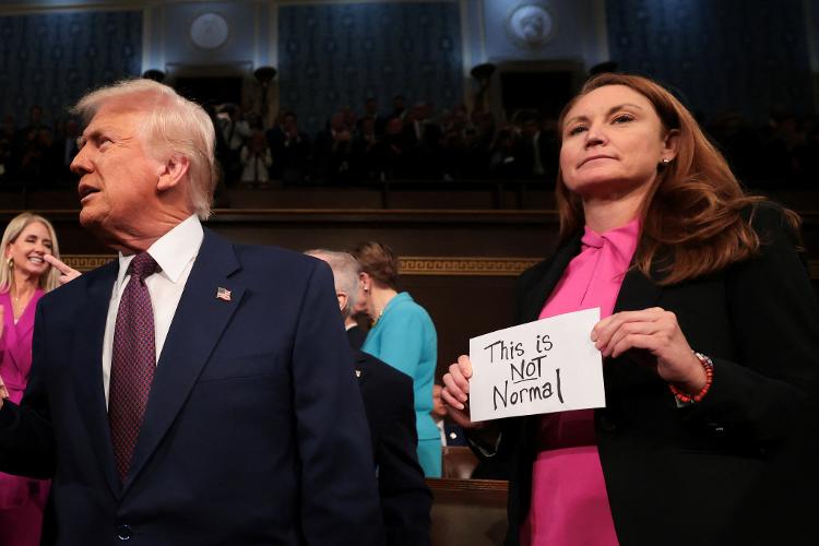 Ao lado do presidente republicano Donald Trump, a congressista democrata Melanie Stansbury segura um cartaz que diz: "Isso não é normal". Trump fez hoje seu primeiro discurso do segundo mandato aos congressistas no Capitólio Ao lado do presidente republicano Donald Trump, a congressista democrata Melanie Stansbury segura um cartaz que diz: "Isso não é normal". Trump fez hoje seu primeiro discurso do segundo mandato aos congressistas no Capitólio