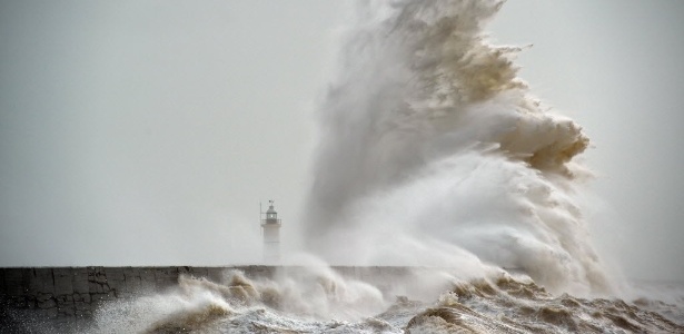 Ondas quebram sobre o farol Newhaven, na costa sul da Inglaterra, durante a recente tempestade que atingiu o país. Ventos fortes de mais de 150 km/h atingiram a região no dia anterior, forçando o fechamento de estradas e de ferrovias. Áreas ficaram alagadas na Inglaterra e no País de Gales - Glyn Kirk/AFP