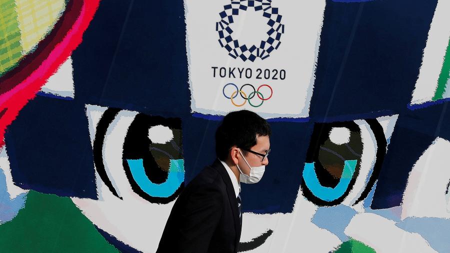 Pedestre caminha em frente a pôster da Olimpíada de Tóquio - Kim Kyung Hoon