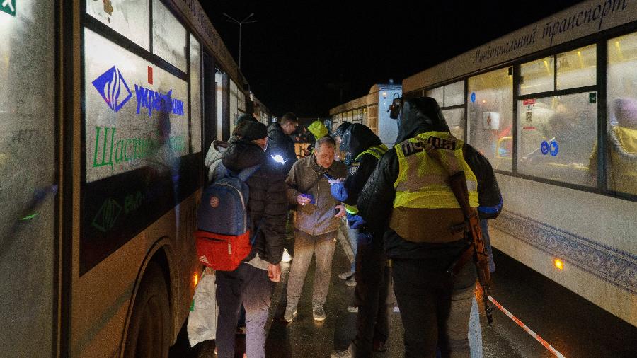Pessoas perto de ônibus enquanto comboio de evacuação chega a um centro de refugiados em Zaporizhzhia, na Ucrânia - EMRE CAYLAK / AFP