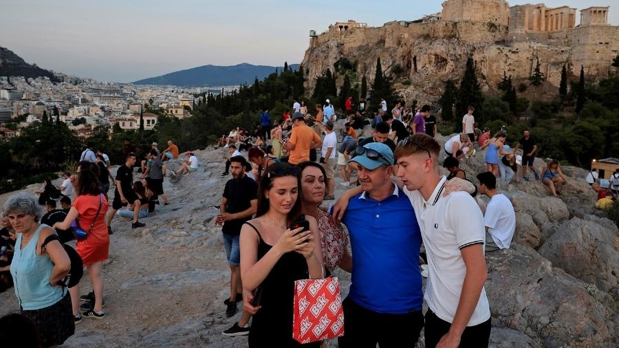 Turistas aproveitam fim da tarde durante visita à Colina Aeropagus, com vista para a Acrópole