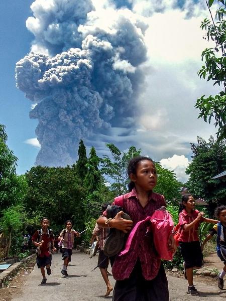 Crianças correm durante a erupção do Monte Lewotobi Laki-Laki, vista da vila de Lewolaga em East Flores