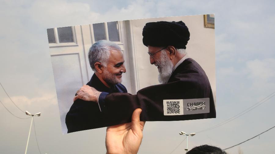 Manifestante segura foto do general Soleimani com o aiatolá do Irã, Ali Khamenai - ATTA KENARE / AFP
