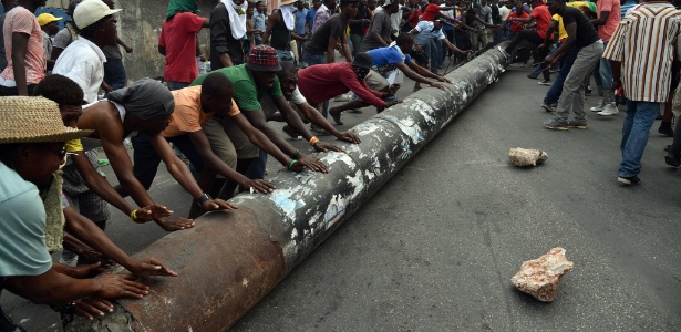 Manifestantes usam poste para bloquear rua em Porto Príncipe, no Haiti - HECTOR RETAMAL/AFP