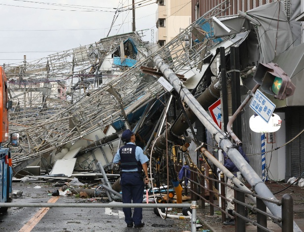 Policial observa os estragos feitos pelo tufão em Osaka, no Japão, na terça-feira (4), antes do terremoto - JIJI PRESS / AFP