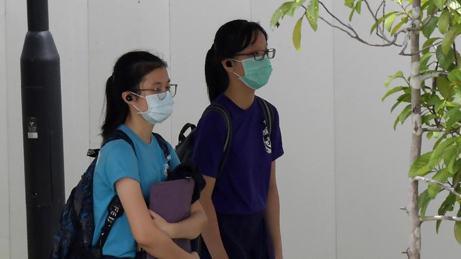 Estudantes que usam máscaras, como medida preventiva contra o novo coronavírus covid-19, voltam para casa da escola em Singapura em 25 de março de 2020 - ROSLAN RAHMAN/AFP