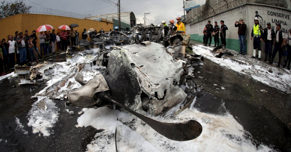 21.nov.2015 - Equipes de resgate e policiais observam os restos de um acidente de avião ocorrido na Cidade da Guatemala. A aeronave de pequeno porte caiu logo após decolar do aeroporto internacional La Aurora, com dois tripulantes a bordo, que foram levados ao hospital com ferimentos leves