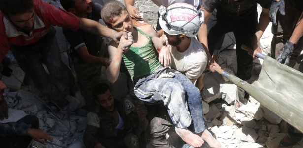 Voluntários resgatam menino de escombros após bombardeio em Aleppo em 25 de julho - Thaer Mohammed/AFP