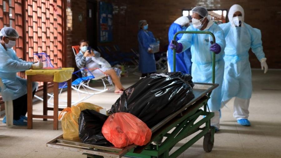 4.mai.2020 - Embalados em plástico, mortos por coronavírus são transferidos por funcionários de hospital em Iquitos, no Peru - Getty Images