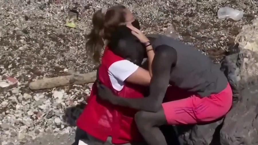 Imagem do momento que voluntária da Cruz Vermelha abraça imigrante  - Reprodução/Youtube/Guardian News
