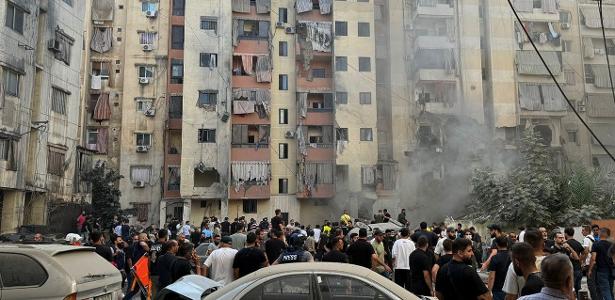 Moradores perto de escombros causados por bombardeio de Israel na periferia de Beirute, no Líbano