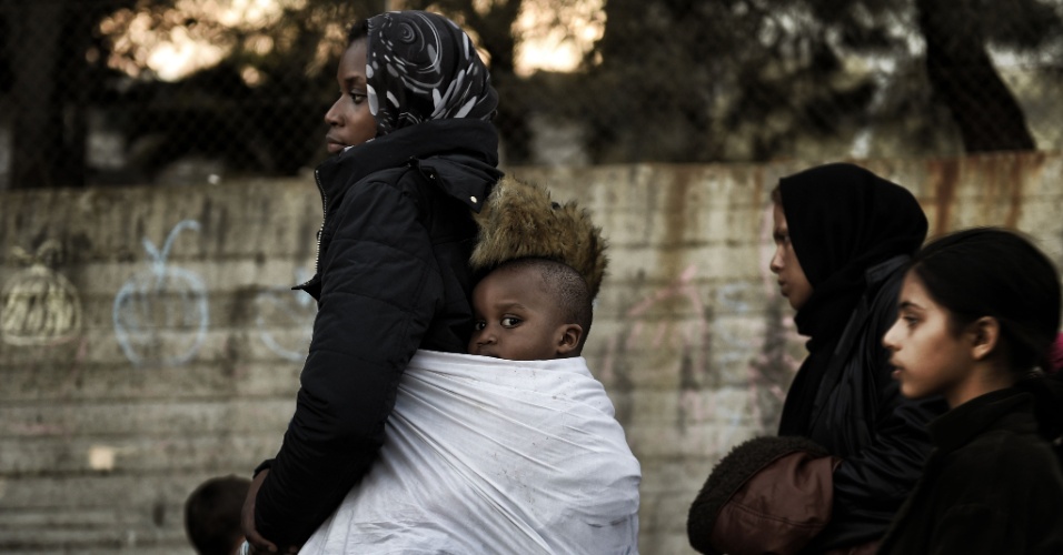 12.nov.2015 - Mulher carrega uma criança nas costas próximo a um centro de registro de imigrantes na ilha grega de Lesbos. Desde o início do verão, a região se tornou porta de entrada de refugiados para a Europa
