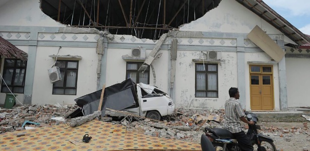 Homem passa diante de prédio destruído pelo terremoto em Pidie Jaya, na província de Aceh, Indonésia - Chaideer Mahyuddin/ AFP