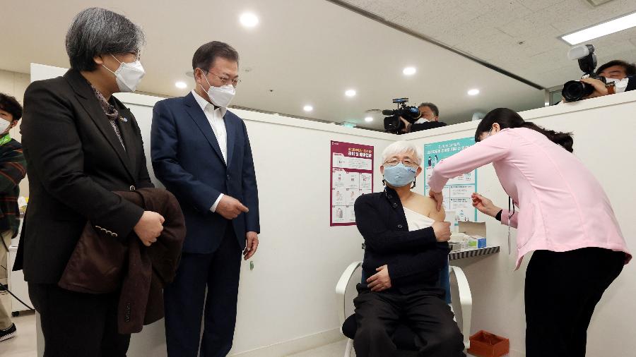 O presidente sul-coreano Moon Jae-in observa profissional da saúde recebendo a primeira dose da vacina da AstraZeneca contra a covid-19 em um centro de saúde em Seul - Yonhap/AFP