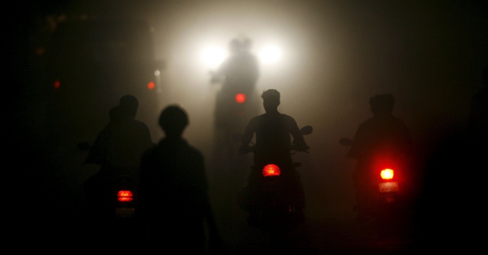 2.out.2015 - Motociclistas passam por estrada coberta com névoa na cidade de Vapi, cerca de 180 km ao norte de Mumbai, na Índia