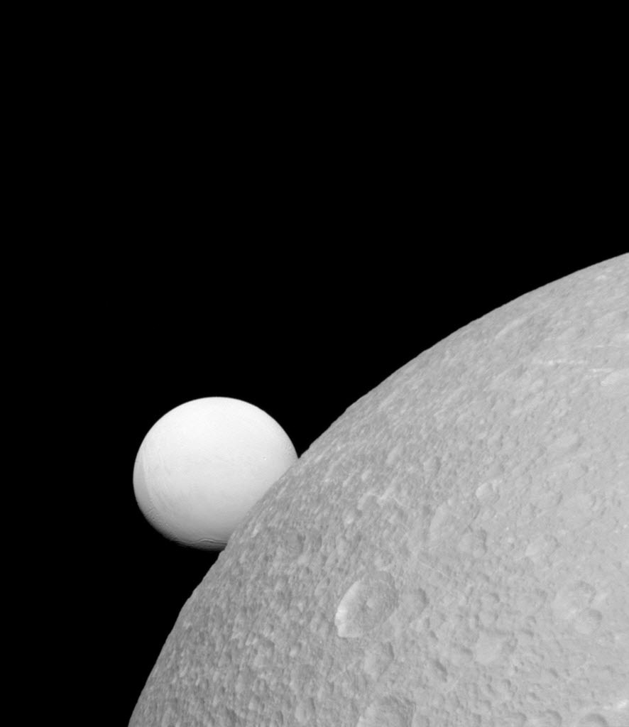 18.11.2015 - Imagem registrada pela câmera da sonda norte-americana Cassini revela Dione (primeiro plano) e Enceladus (ao fundo), luas do planeta Saturno. Apesar dos dois satélites possuírem o mesmo material, Enceladus tem refletividade bem maior do que Dione. Assim, parece mais brilhante contra o céu escuro da noite.