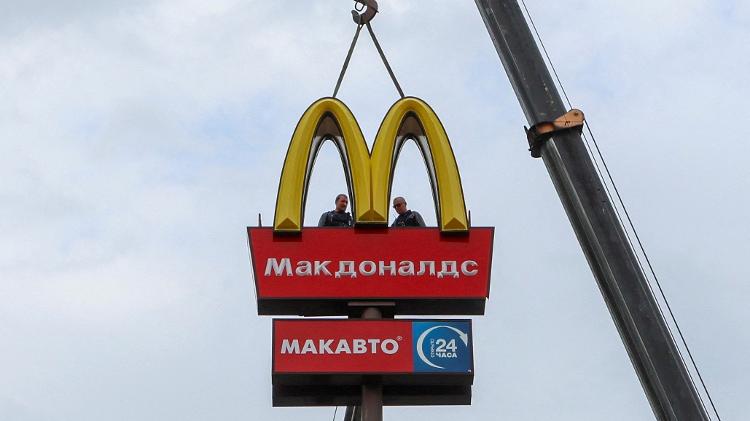 Trabalhadores usam guindaste para desmontar os arcos dourados do McDonald's na cidade russa de Kingisepp