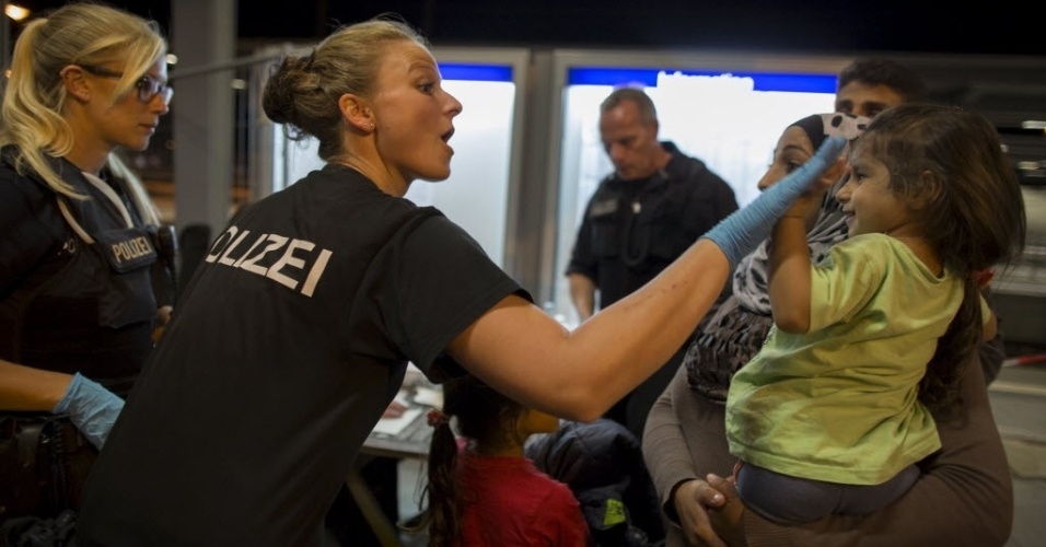 18.set.2015 - Uma policial alemã brinca com Hanine, 3, refugiada síria vinda de Dir al-Zour, na estação ferroviária de Rosenheim, na Alemanha. Antes de entrarem no país, os refugiados sírios são levados a uma delegacia onde passam por um interrogatório, fazem exames médicos e de impressões digitais
