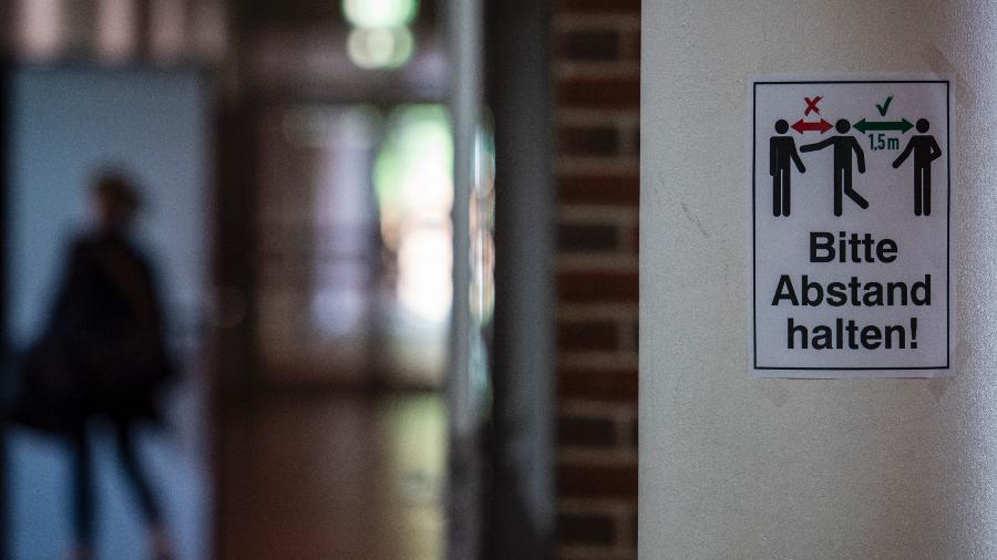 Uma placa com a inscrição: "Mantenha sua distância" é exibida em um corredor em uma escola de Rostock, norte da Alemanha - John MACDOUGALL / AFP