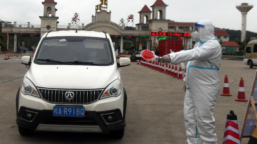 Trabalhador vestindo roupa de proteção contra a covid-19 se prepara para verificar carro em pedágio na cidade de Fangchenggang, na China - Jiang Xueling/China News Service via Getty Images