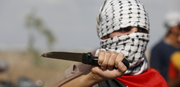 Palestino mascarado exibe faca durante protesto próximo à fronteira da faixa de Gaza com Israel - Mohammed Salem/Reuters