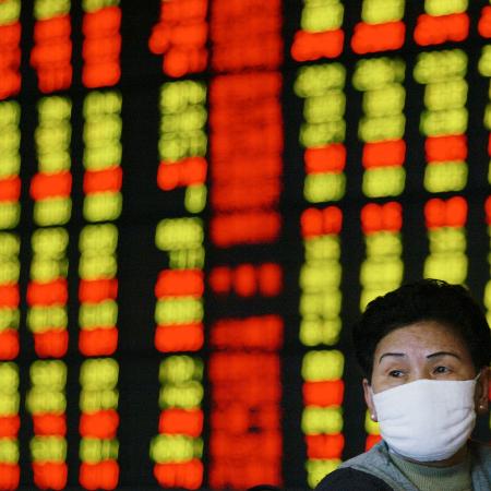 Investidora usa máscara de prevenção contra vírus enquanto monitora ações em Xangai, China - Claro Cortes