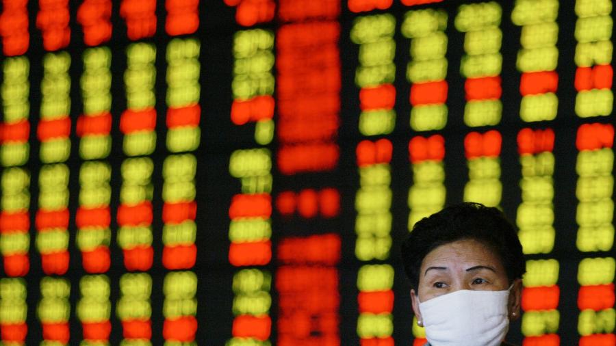 Investidora usa máscara de prevenção contra vírus enquanto monitora ações em Xangai, China - Claro Cortes