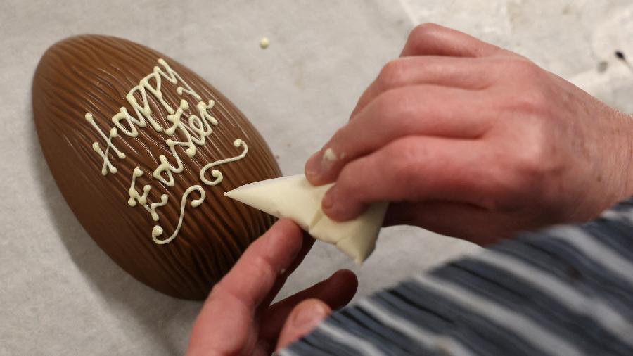 Um trabalhador escreve uma mensagem em um ovo de Páscoa feito à mão na loja Kennedys Fine Chocolates em Orton, Grã-Bretanha - Phil Noble/Reuters