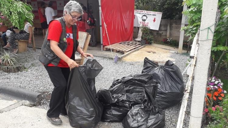 Militante recolhe lixo no local onde estava instalada a Vigília Lula Livre - Vinícius Konchinski/UOL