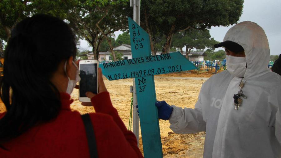 Familiar faz foto da cruz de Arnobio Alves Bezerra, 71, vítima da covid-19, no Cemitério Nossa Senhora Aparecida, em Manaus - EDMAR BARROS/FUTURA PRESS/ESTADÃO CONTEÚDO