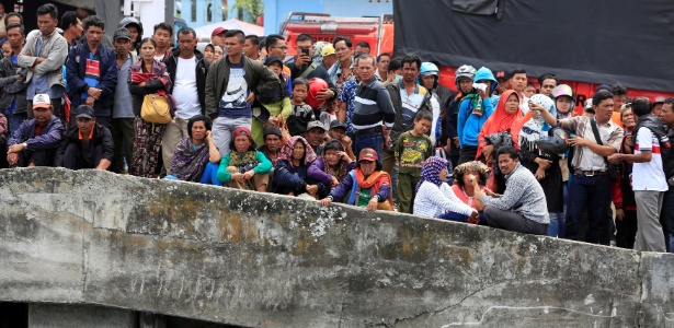 Moradores e parentes observam no pier do porto de Tigaras o trabalho de resgate dos passageiros que estavam no acidente do ferry boat no lago Toba, na última segunda (18) - BEAWIHARTA/Reuters