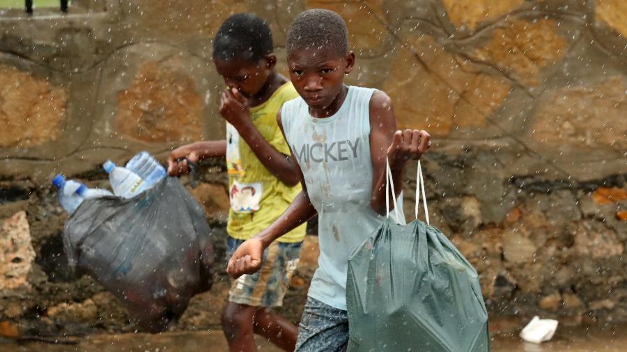 30.abr.2019 - Crianças caminham por uma rua inundada enquanto chove em Pemba, após a passagem do ciclone Kenneth em Moçambique - Mike Hutchings/Reuters