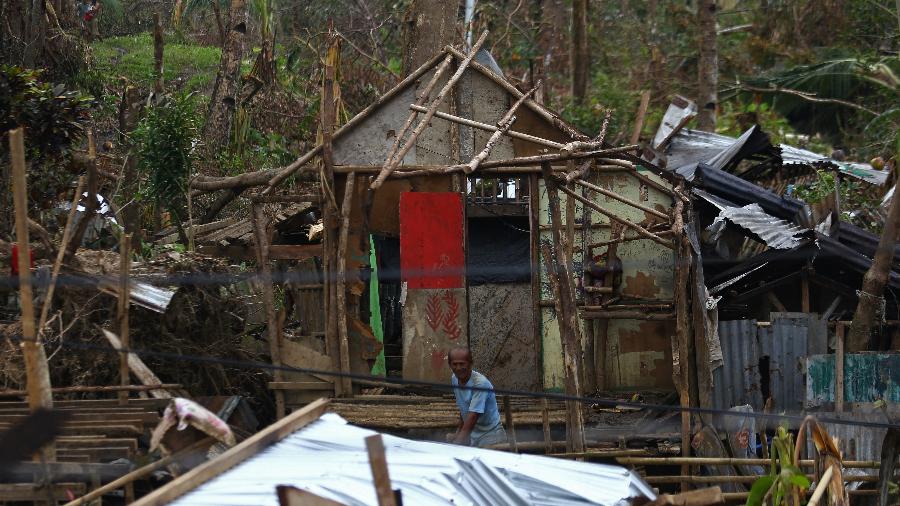 24.dez.2021 - Morador recolhe madeira enquanto tenta consertar sua casa danificada na cidade de Surigao, dias após o supertufão Rai devastar a cidade - Ferdinandh Cabrera/AFP