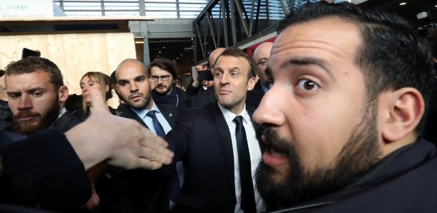 Benalla aparece em primeiro plano em foto de fevereiro, com Macron ao fundo (de gravata preta); "senhor segurança" foi demitido em 20 de julho - Reuters
