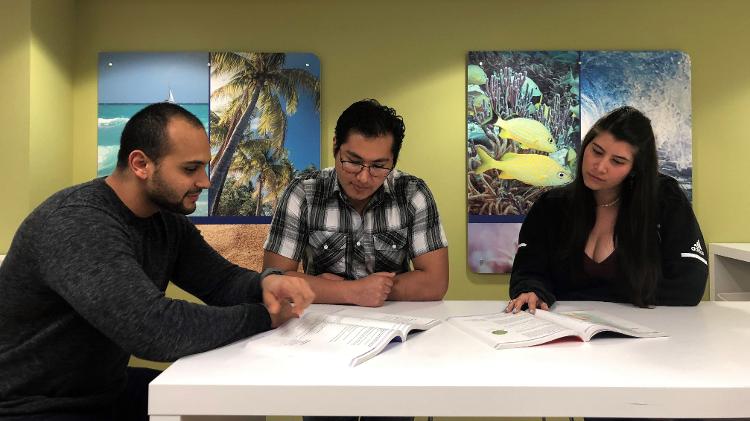23.mar.2019 - Os médicos venezuelanos Martitza Luna (direita) e Victor Guillén (esquerda) e o boliviano Álvaro Soria (centro) conversam durante um recesso de aulas no dia 21 de março no Kaplan Center em Miami, Flórida - Celeste Rodas de Juarez/EFE - Celeste Rodas de Juarez/EFE