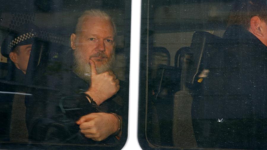 11.abr.2019 - Julian Assange, fundador do WikiLeaks, acena com as mãos algemadas, de dentro da van da polícia britânica após ser preso na embaixada do Equador, em Londres - Henry Nicholls/Reuters