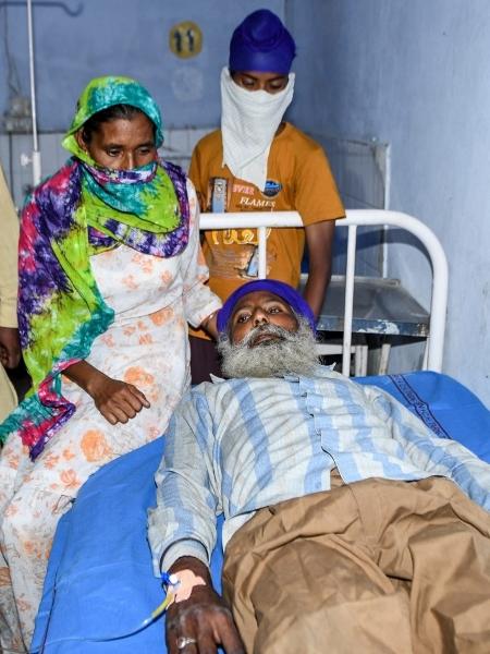 Familiares junto a paciente em hospital de Tarn Taran, na Índia, após supostamente ter ingerido álcool clandestino - Narinder Nanu/AFP