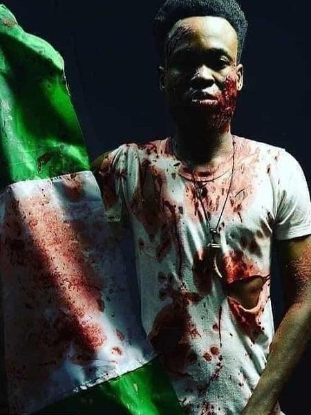 Manifestante posa com a bandeira da Nigéria manchada de sangue - Reprodução/WhatsApp