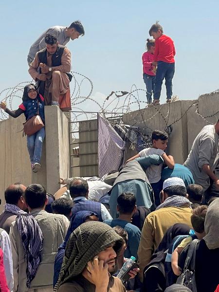16.ago.2021 - Homem puxa uma criança para dentro dos muros do aeroporto internacional de Cabul, Afeganistão - Stringer/Reuters