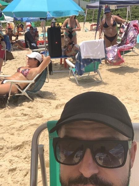Carlos postou selfie na praia; atrás dele, uma caixa de som imensa