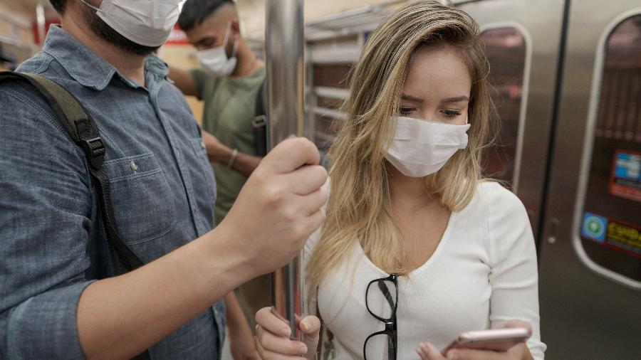Passageiros em metrô usando máscara e celular durante a pandemia - Vergani_Fotografia/Getty Images/iStockphoto