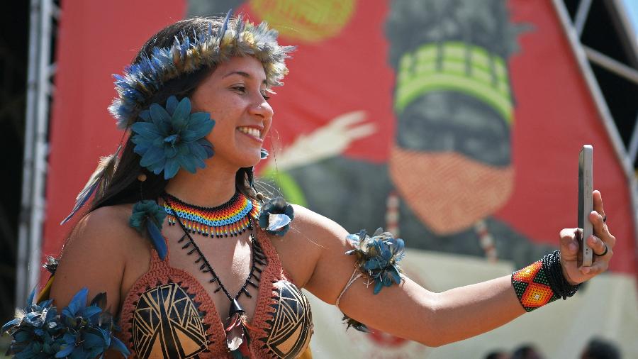 Samela Aiwá, dos Satere Mawe da Amazônia, faz vídeo para publicar nas redes sociais no acampamento indígena Terra Livre, em Brasília - Carl de Souza/AFP