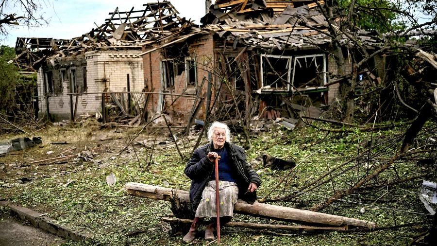 Uma mulher se senta em frente a duas casas que foram demolidas por um ataque de míssil, que matou outra mulher, em Druzhkivka, Donetsk - Getty Images